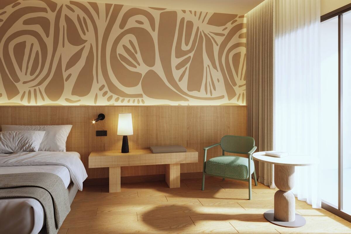 A hotel room with a bed, a desk with a lamp, a chair, a round table, and a large window with curtains.
