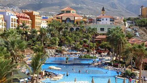 A resort with multiple swimming pools, palm trees, and a mountainous backdrop. - Bahia Principe Explore Costa Adeje – Hyatt Inclusive Collection (Adeje)
