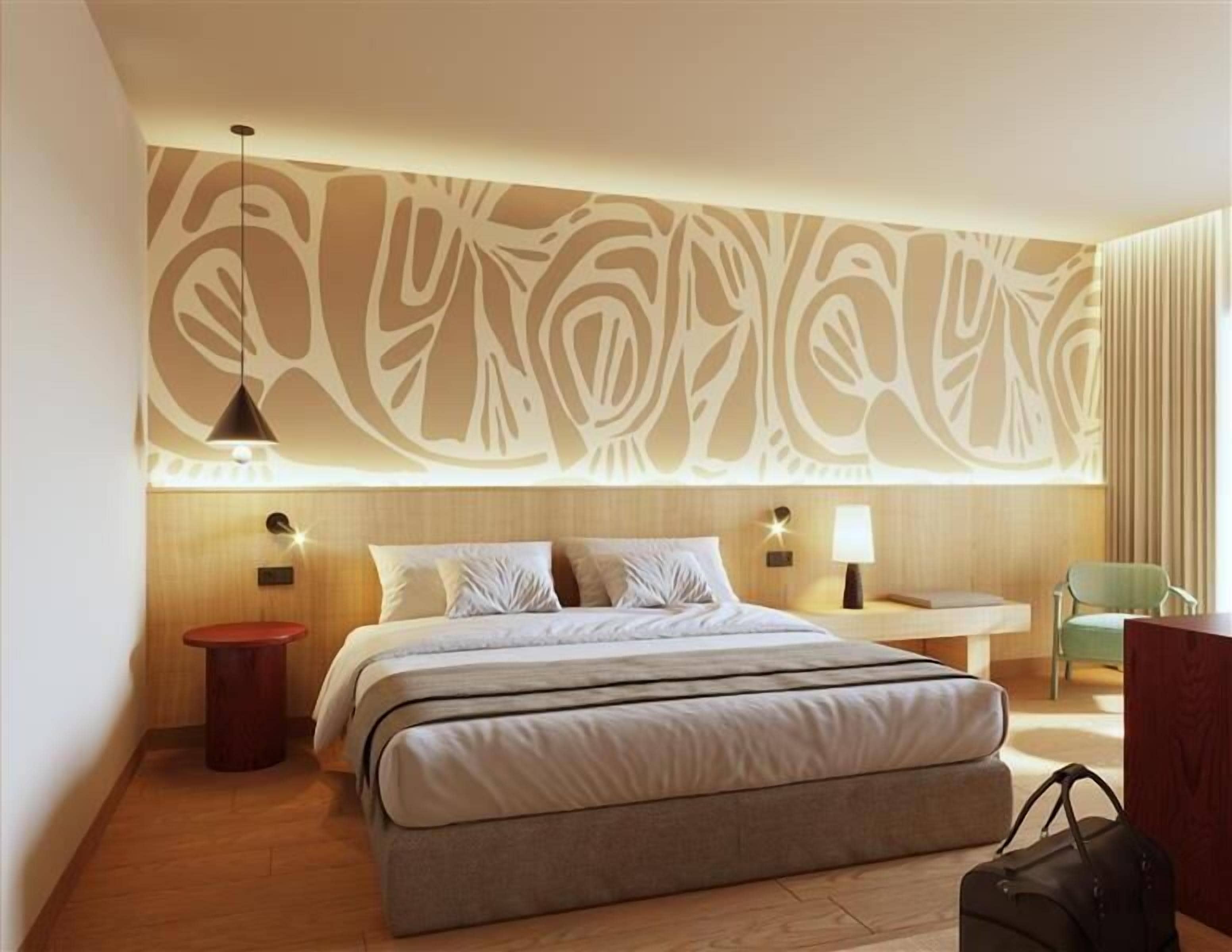 A modern hotel room with a large bed, bedside tables, a wall with abstract patterns, and a hanging light fixture.