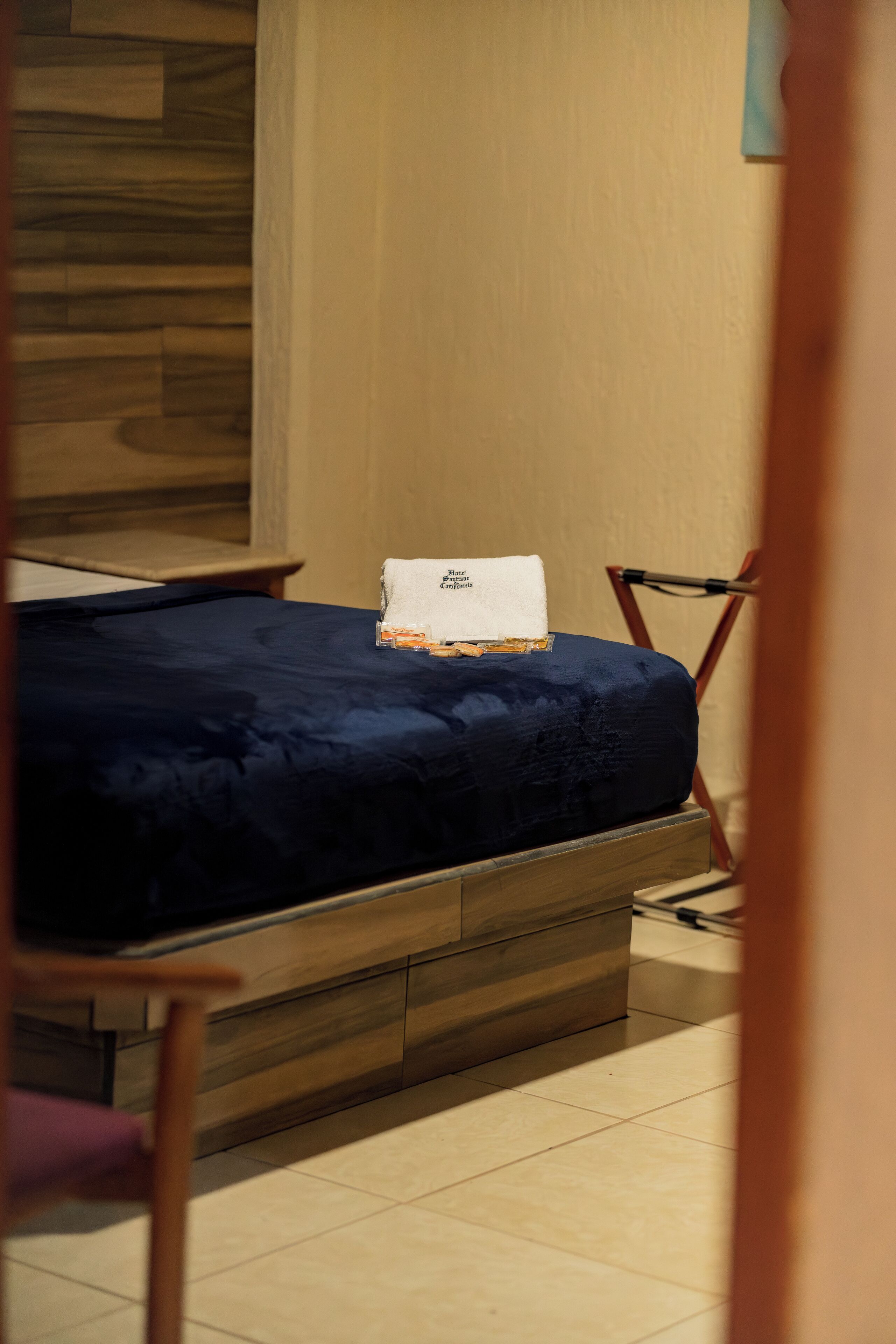 Ein kleines Zimmer mit einem Bett, einem Holzkopfende und einem kleinen Tisch.