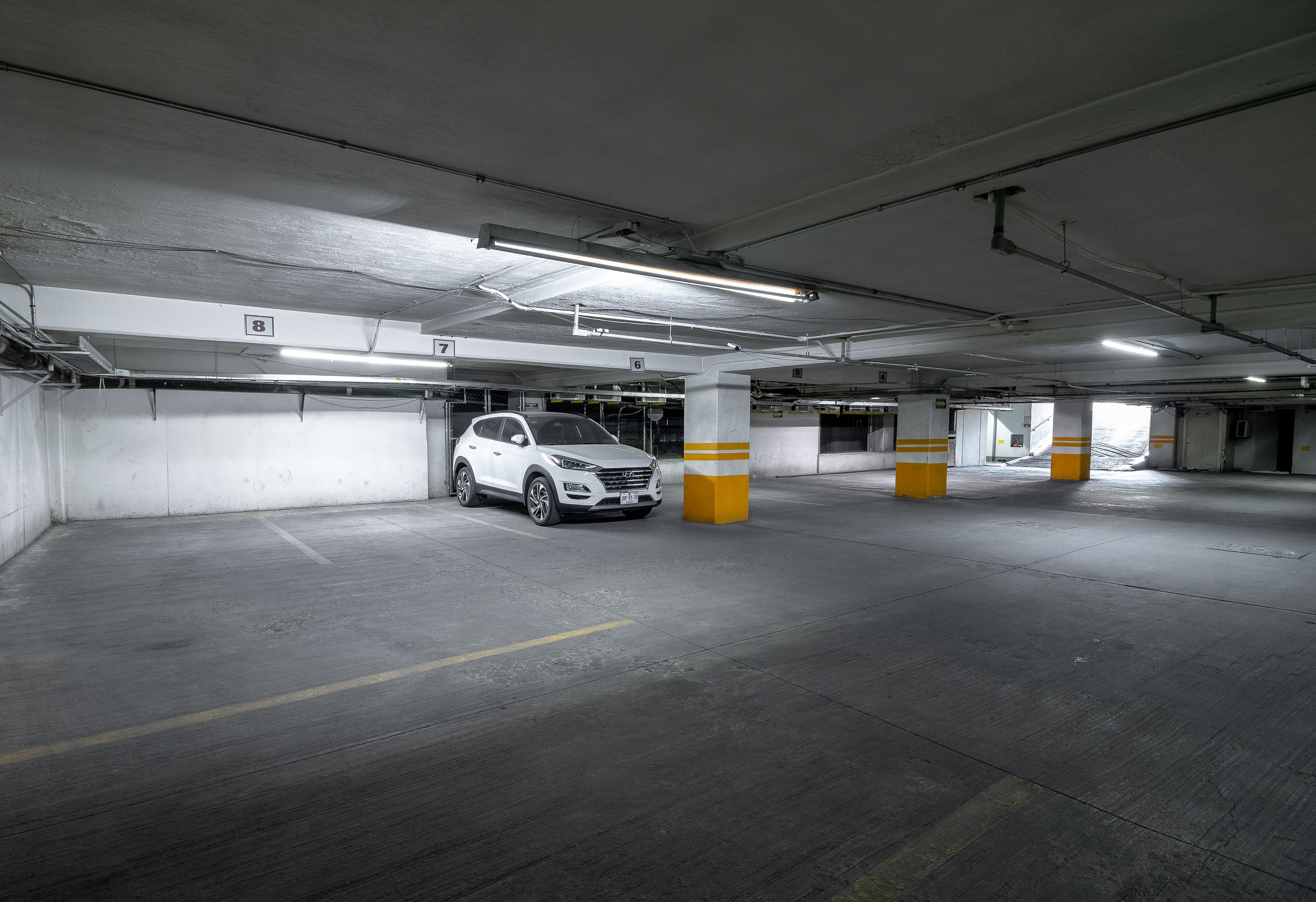 Un estacionamiento de varios niveles con pisos de concreto y pilares amarillos.