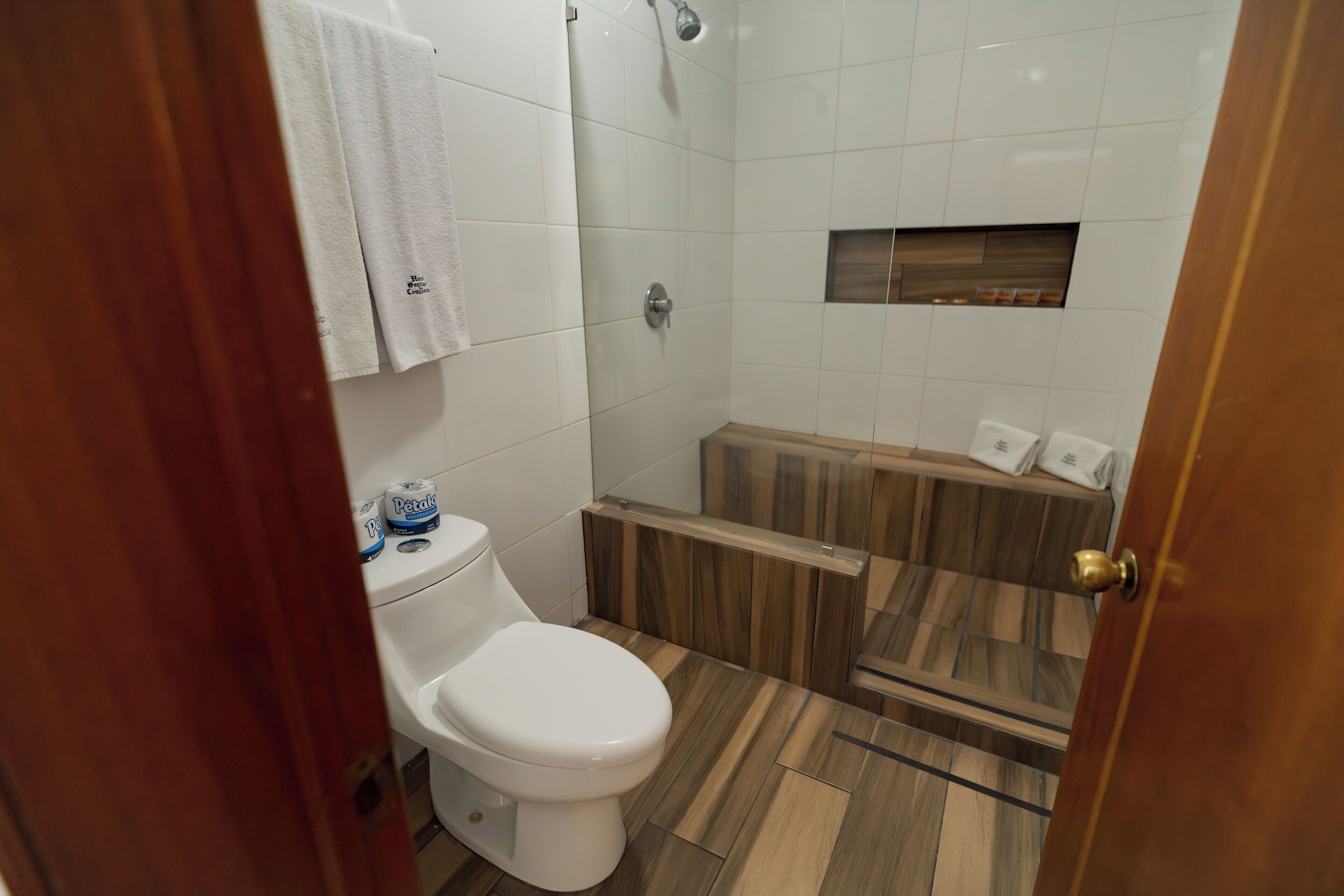 A bathroom with a toilet, shower, and wooden vanity.