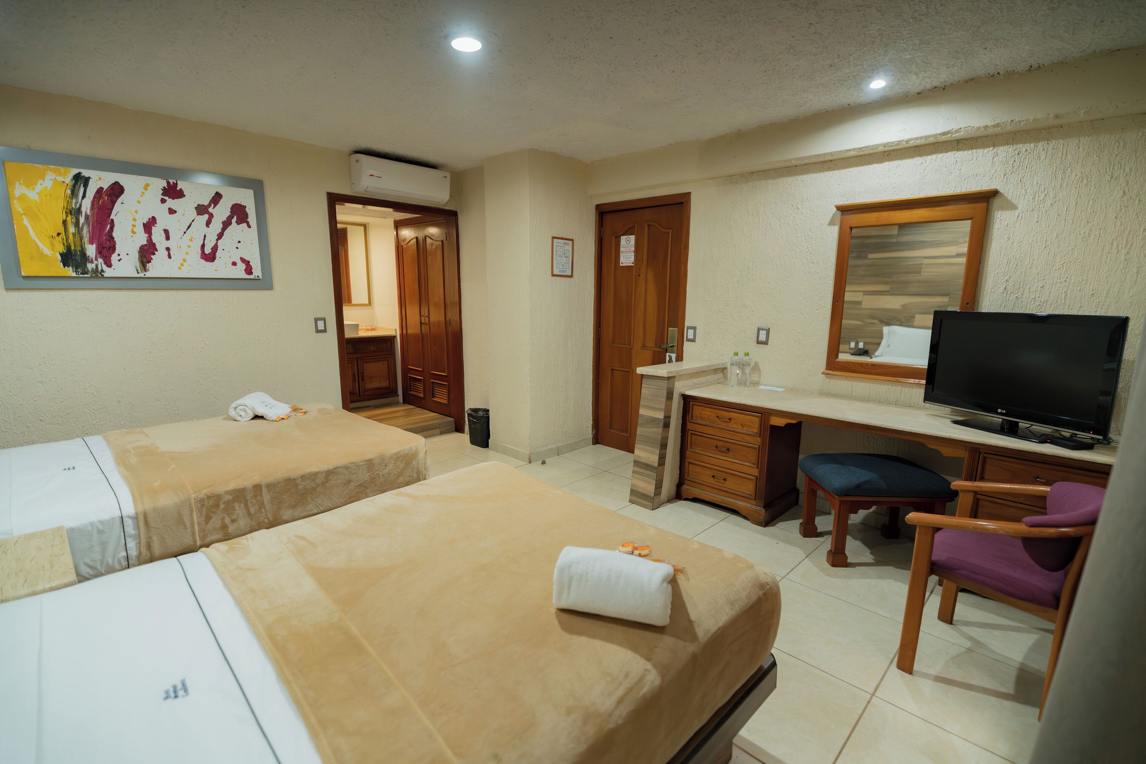 Una habitación de hotel con dos camas, un escritorio, televisor y baño.