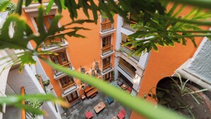 An aerial view of a multi-story building with balconies, outdoor seating, and potted plants.