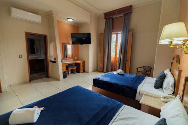 A hotel room with two beds, a desk, a TV, and a window with curtains. - Hotel Santiago de Compostela (Guadalajara)