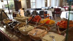 A buffet with various food items and a dining area with tables and chairs.