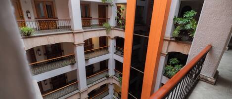 Un atrio de varios niveles con balcones, plantas y una columna central.