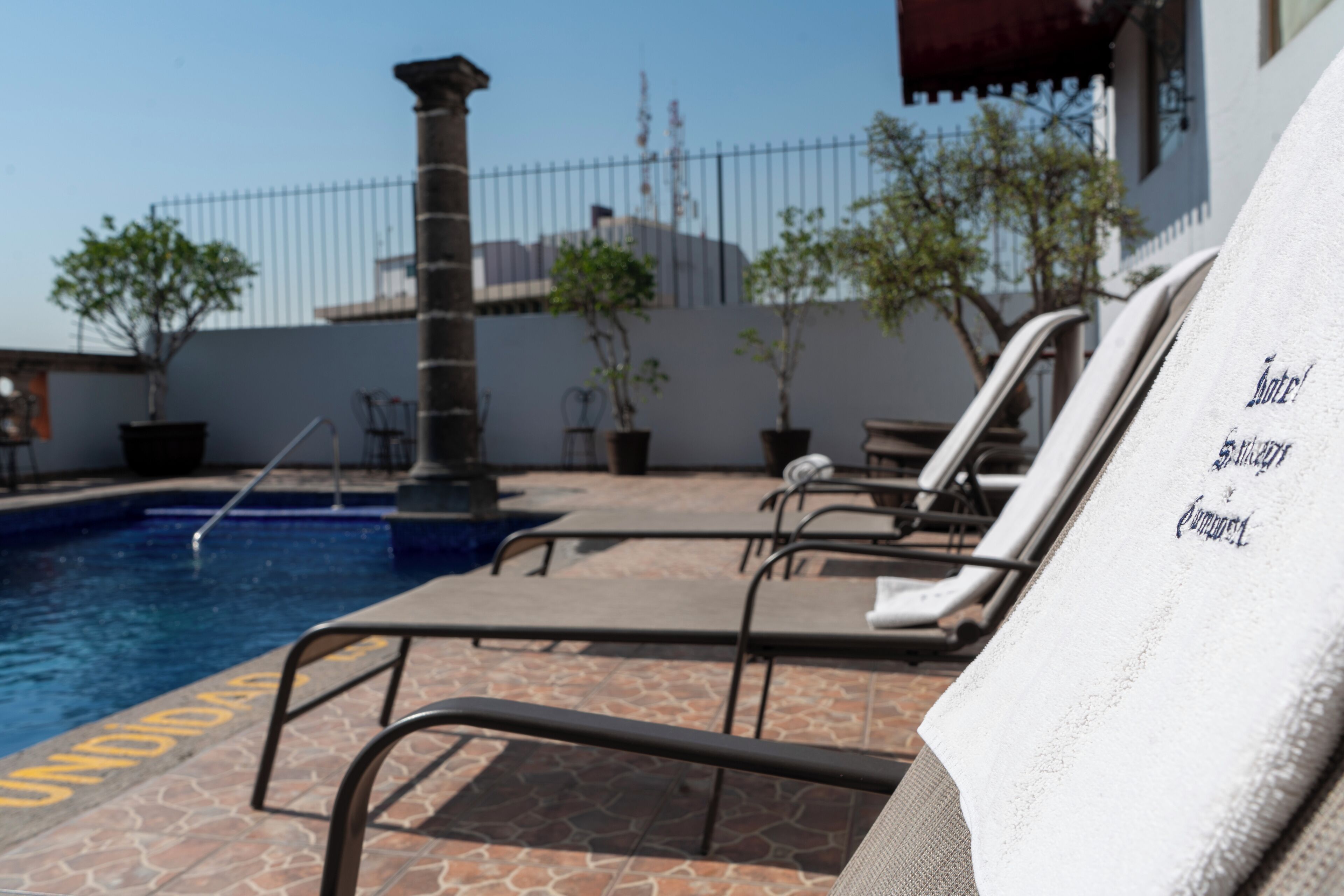 A pool area with lounge chairs and a towel with text.