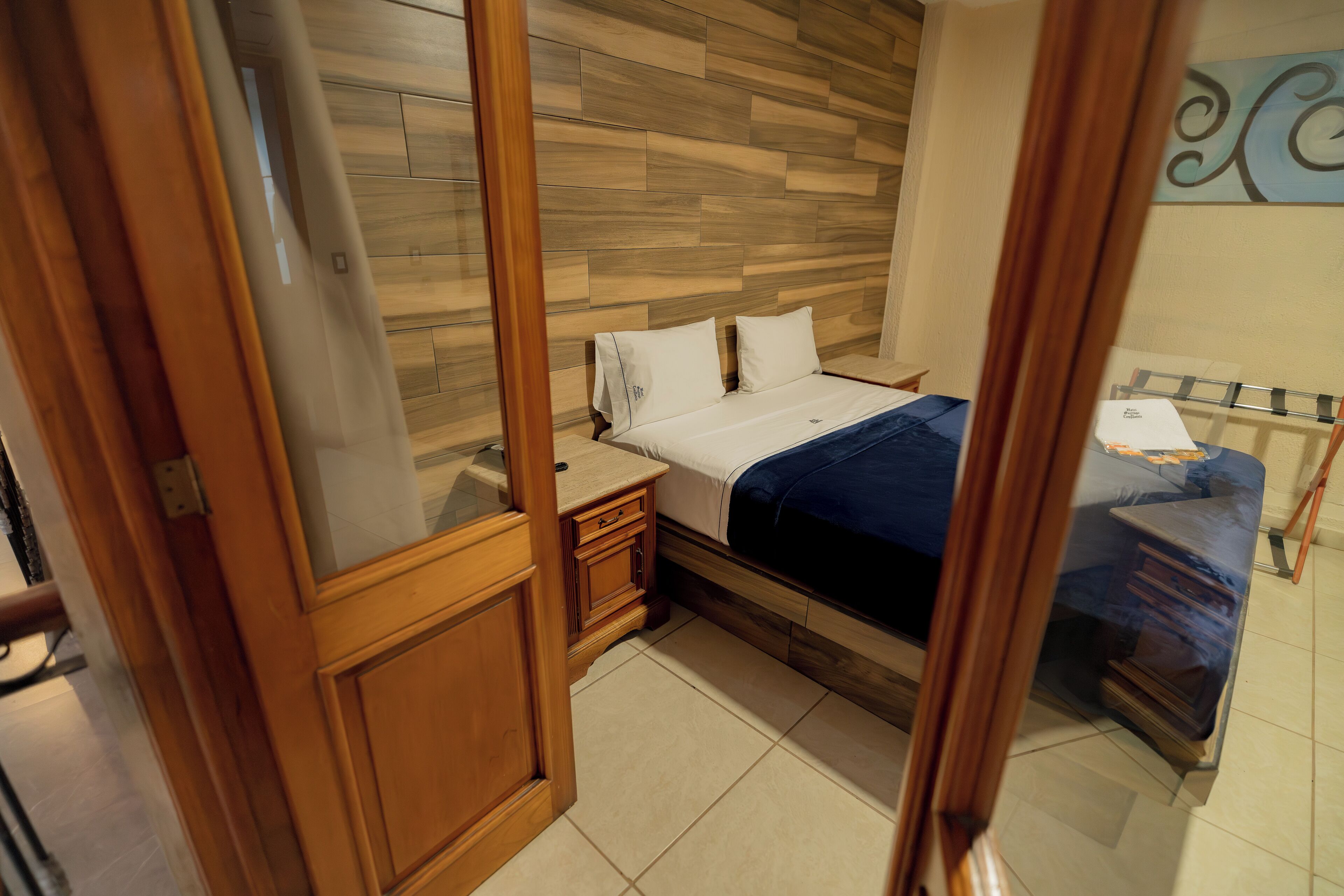 Un dormitorio con cabecera de madera, cama con ropa de cama blanca, mesita de noche y cómoda.