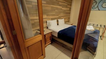 Un dormitorio con cabecera de madera, cama con ropa de cama blanca, mesita de noche y cómoda.