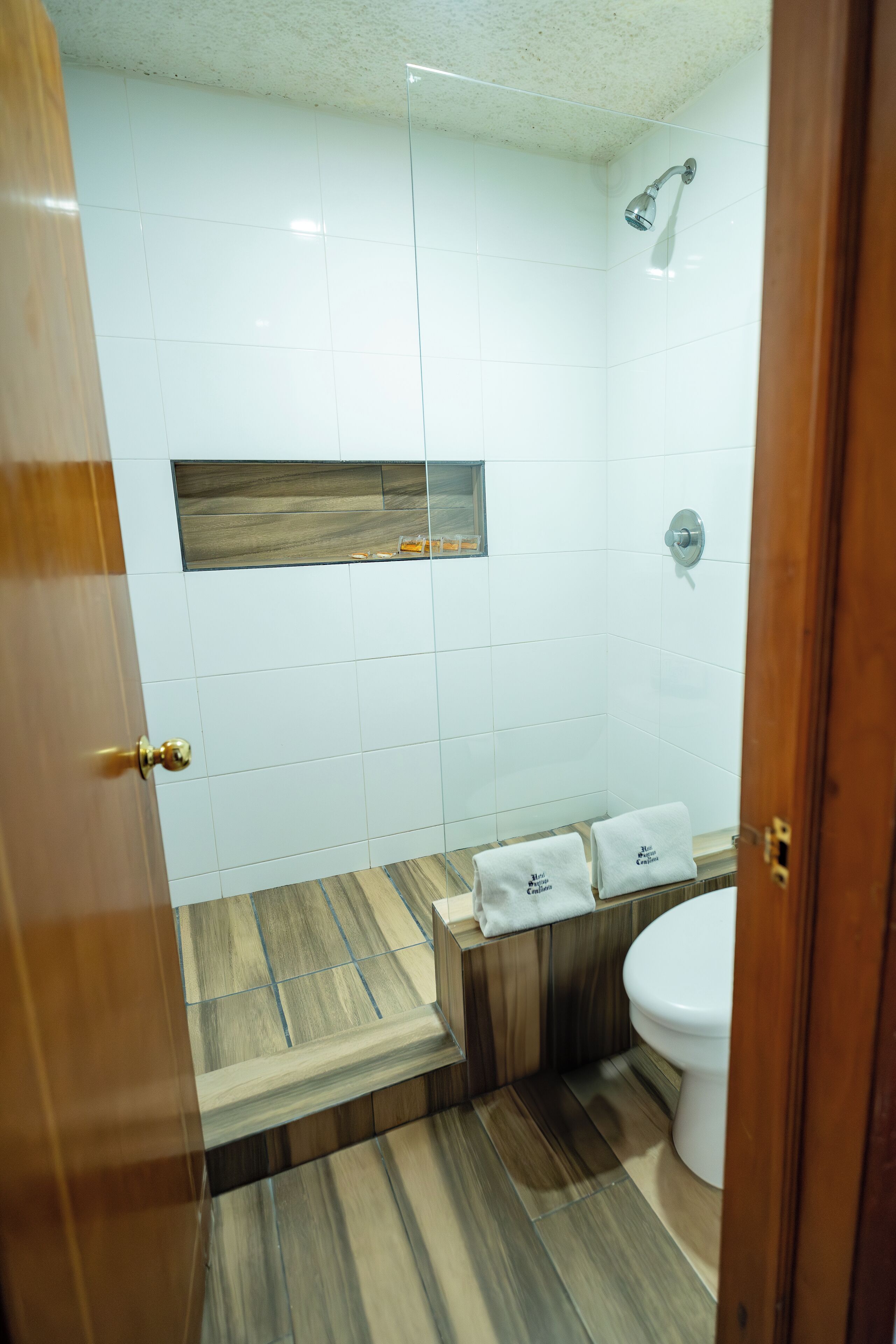 A bathroom with a shower, toilet, and a vanity with towels.