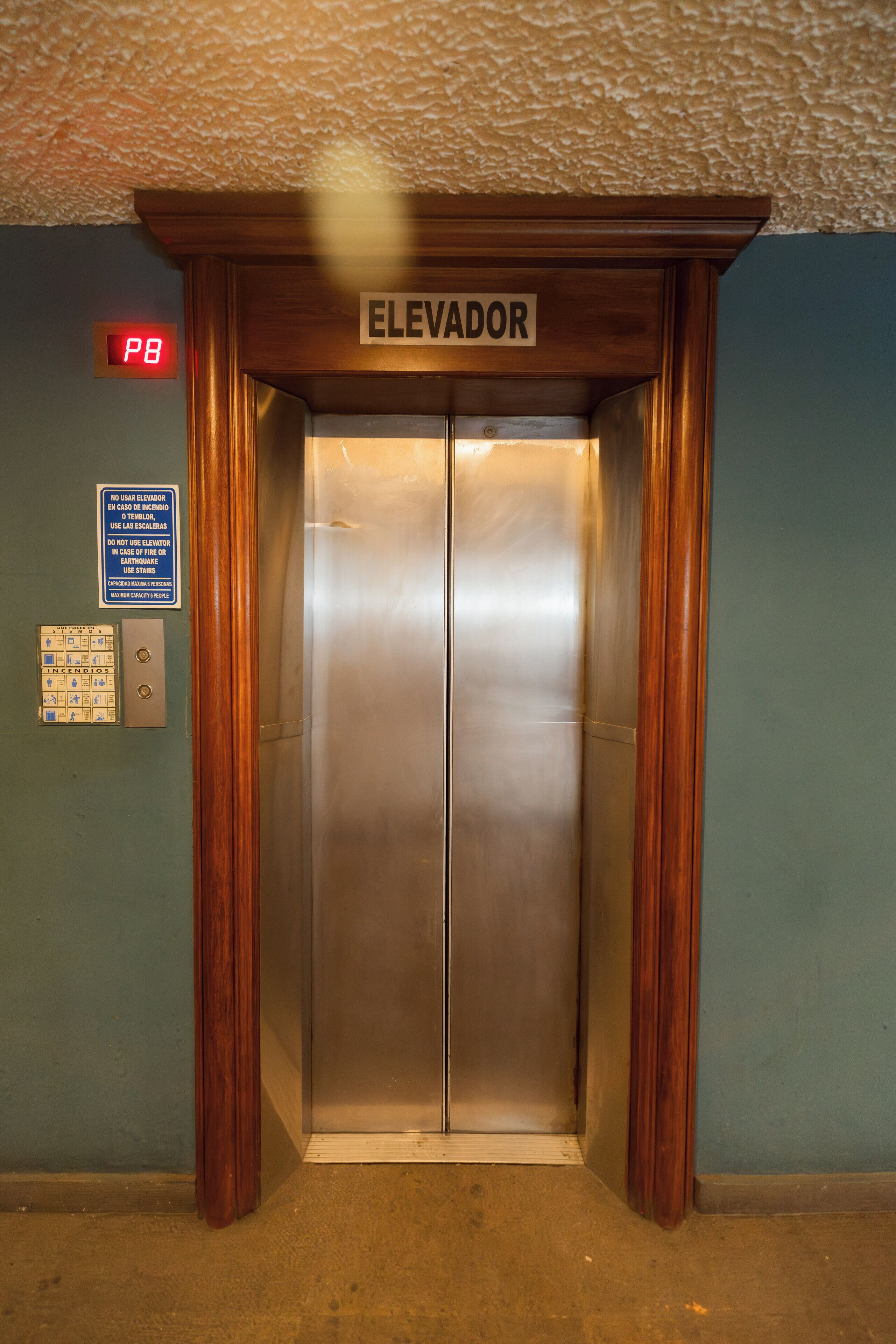 An elevator with a sign that reads "ELEVADOR" and a fire alarm on the wall.