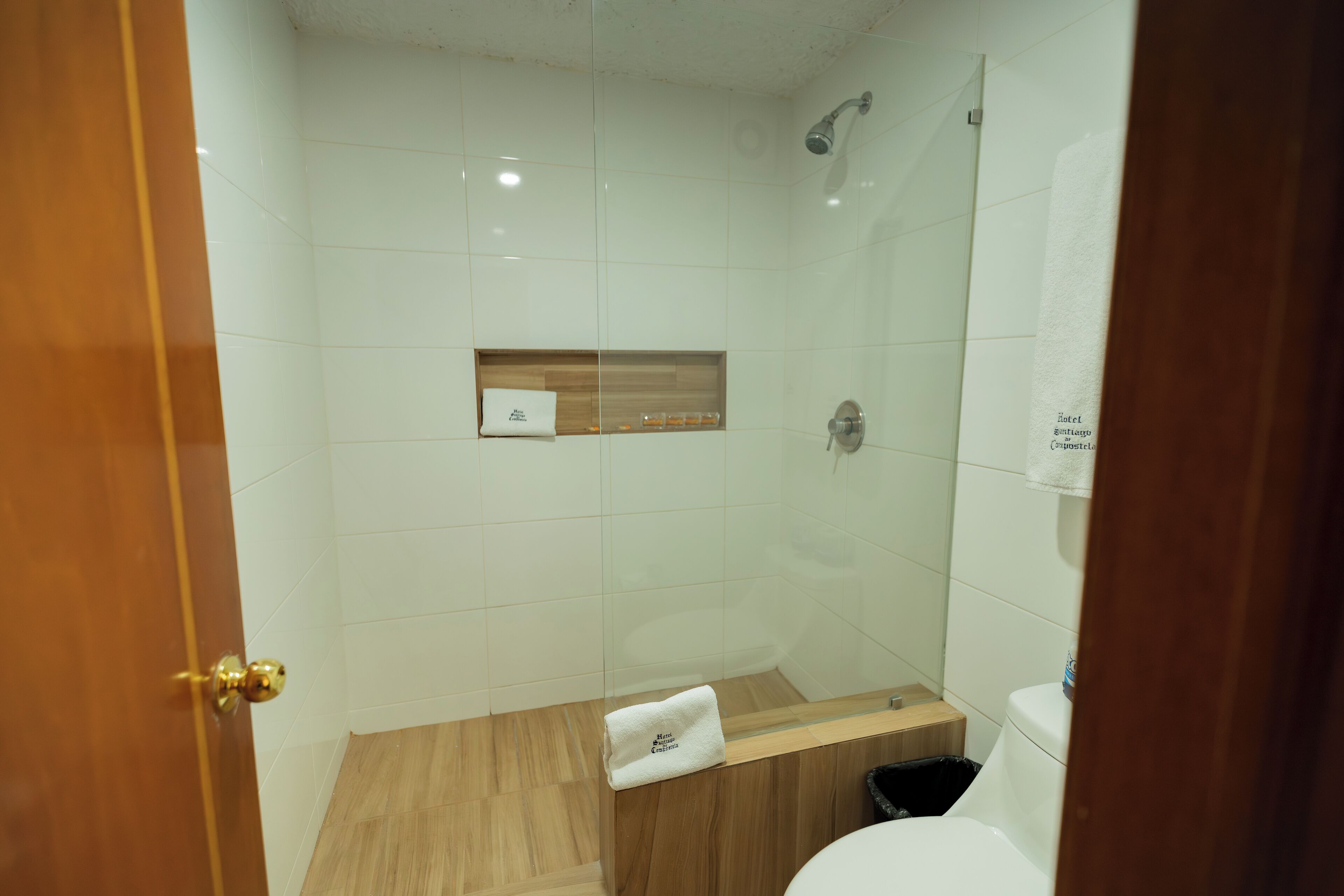 A modern bathroom with a glass shower enclosure, a wooden vanity, and a white toilet.