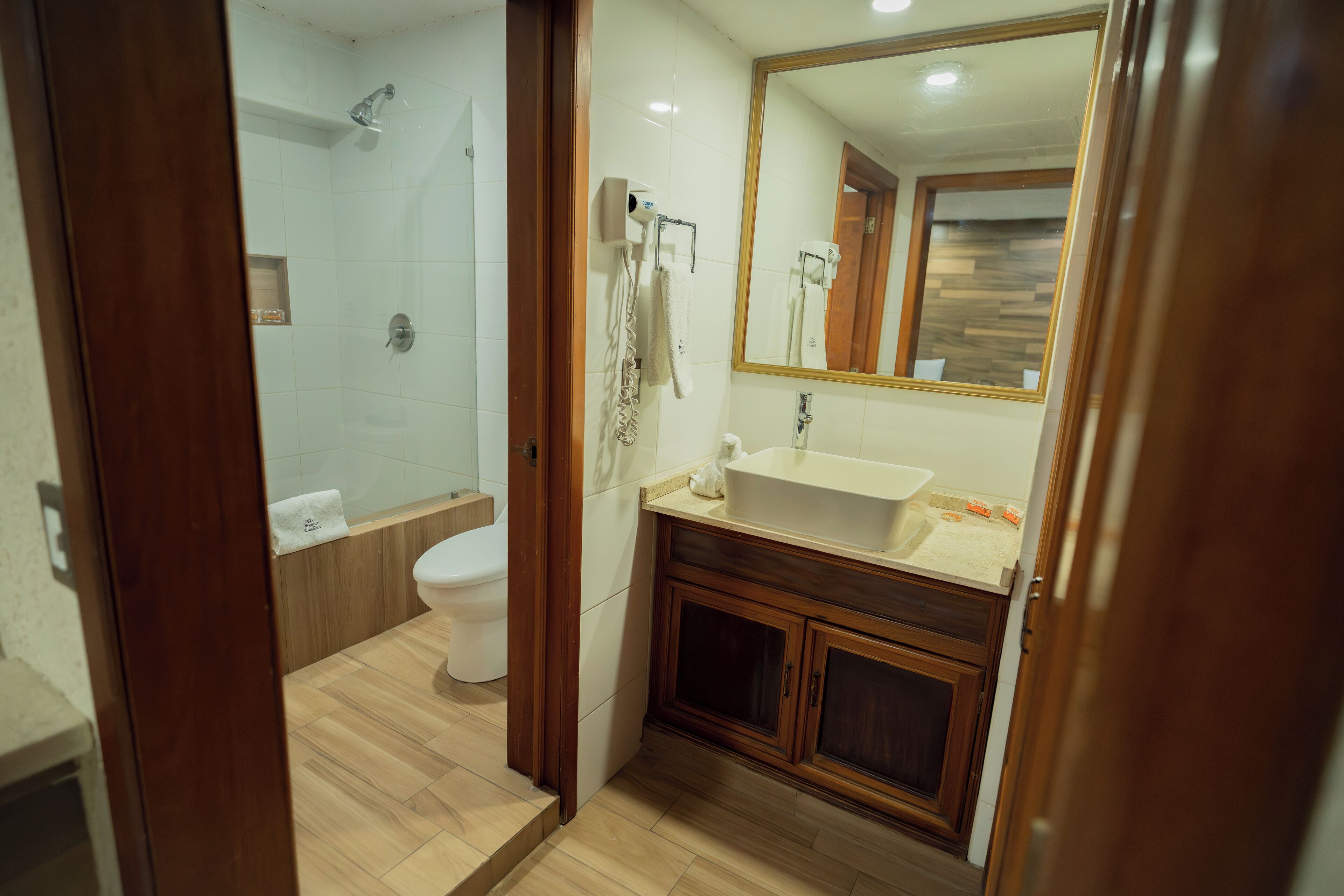 A bathroom with a shower, toilet, sink, and mirror.