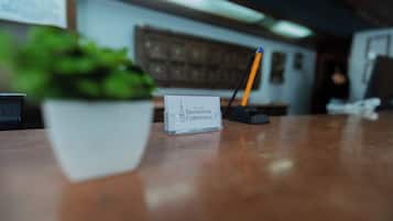 A hotel reception desk with a name card, a potted plant, and a pencil holder.