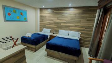 A hotel room with two beds, wooden headboard, a small desk, and a colorful painting on the wall.
