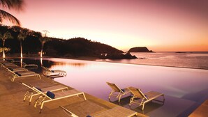 A serene poolside area with lounge chairs and a view of the ocean at sunset. - Dreams Huatulco Resort & Spa - All Inclusive (Santa María Huatulco)