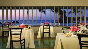 A restaurant with tables set for dining, featuring a view of the ocean and palm trees. - Dreams Huatulco Resort & Spa - All Inclusive (Santa María Huatulco)