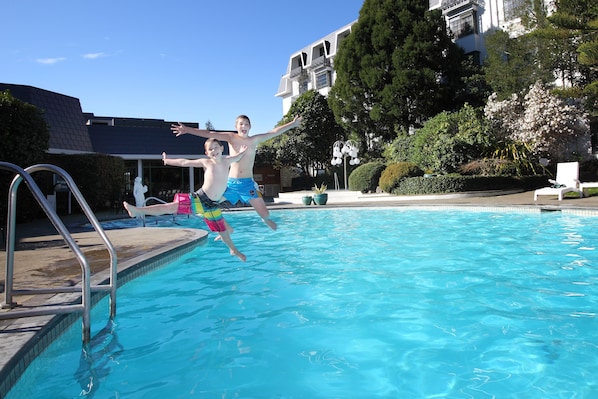 Una piscina al aire libre, sombrillas, sillones reclinables de piscina