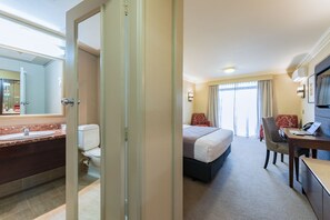 A hotel room with a bathroom, a bed, a desk, and a chair. - Distinction Rotorua Hotel and Conference Centre (Rotorua)