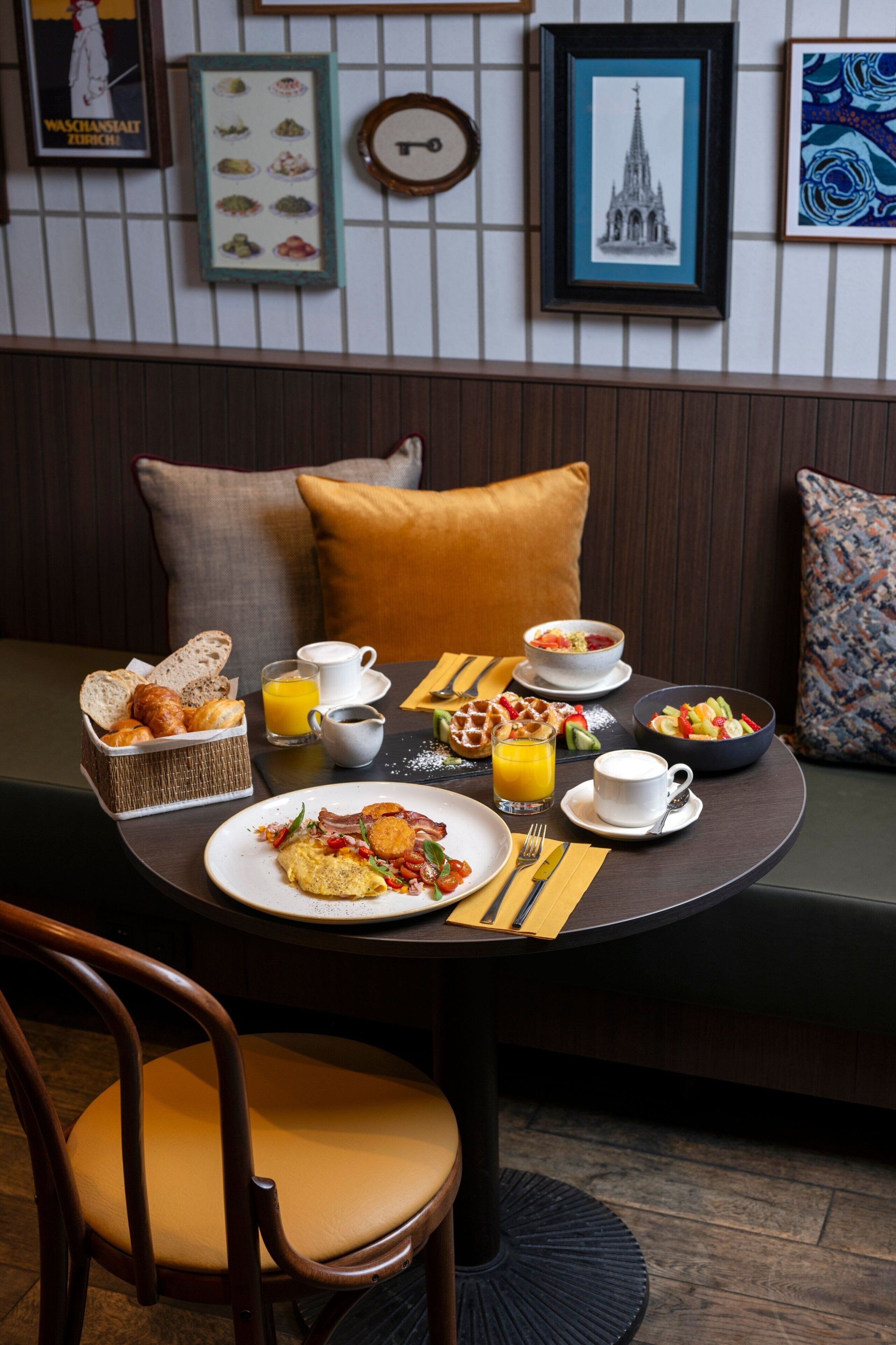 Una escena de desayuno con una mesa, platos de comida y un cuenco de fruta.
