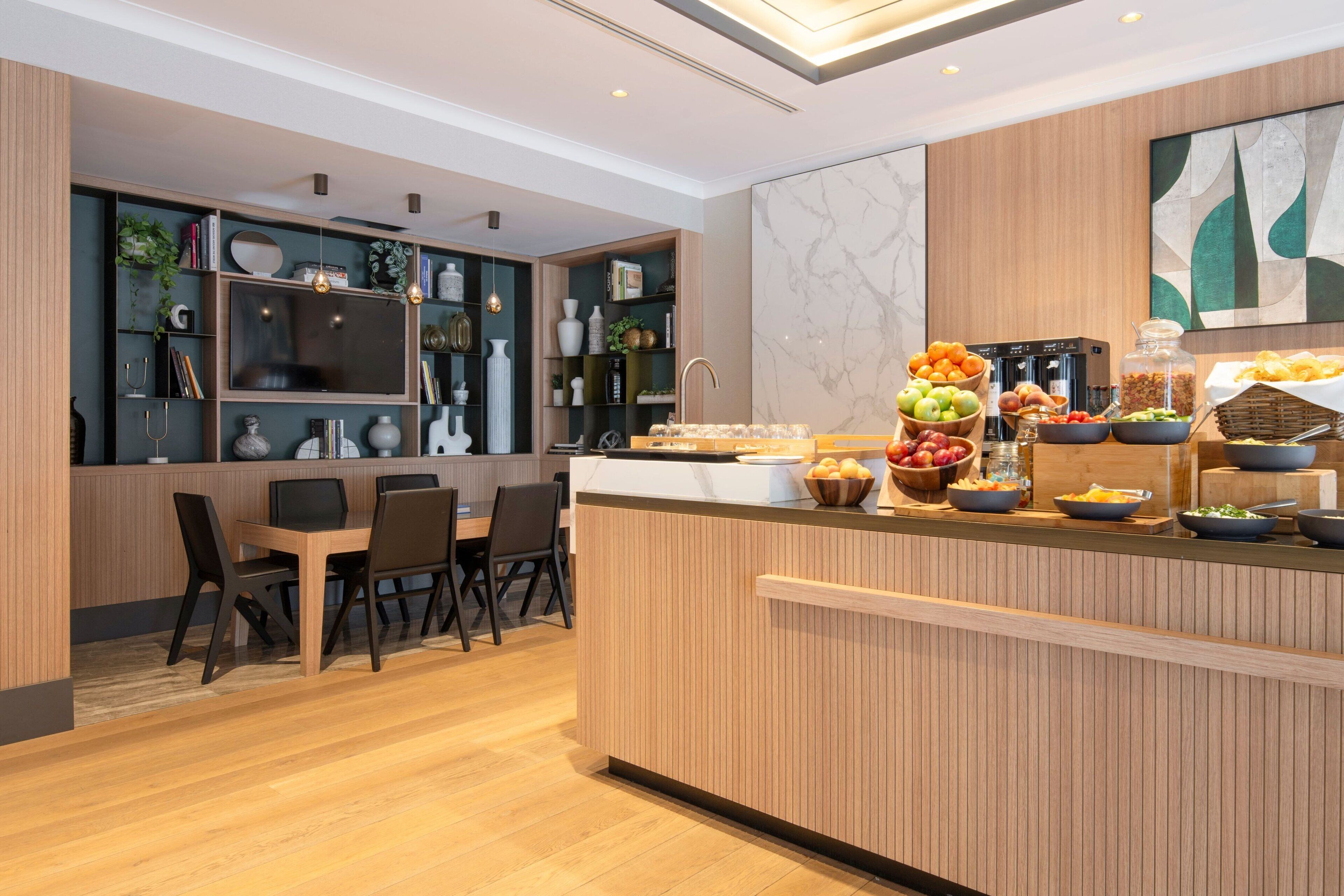 A modern kitchen with a wooden island, built-in shelves, and a dining area with chairs.