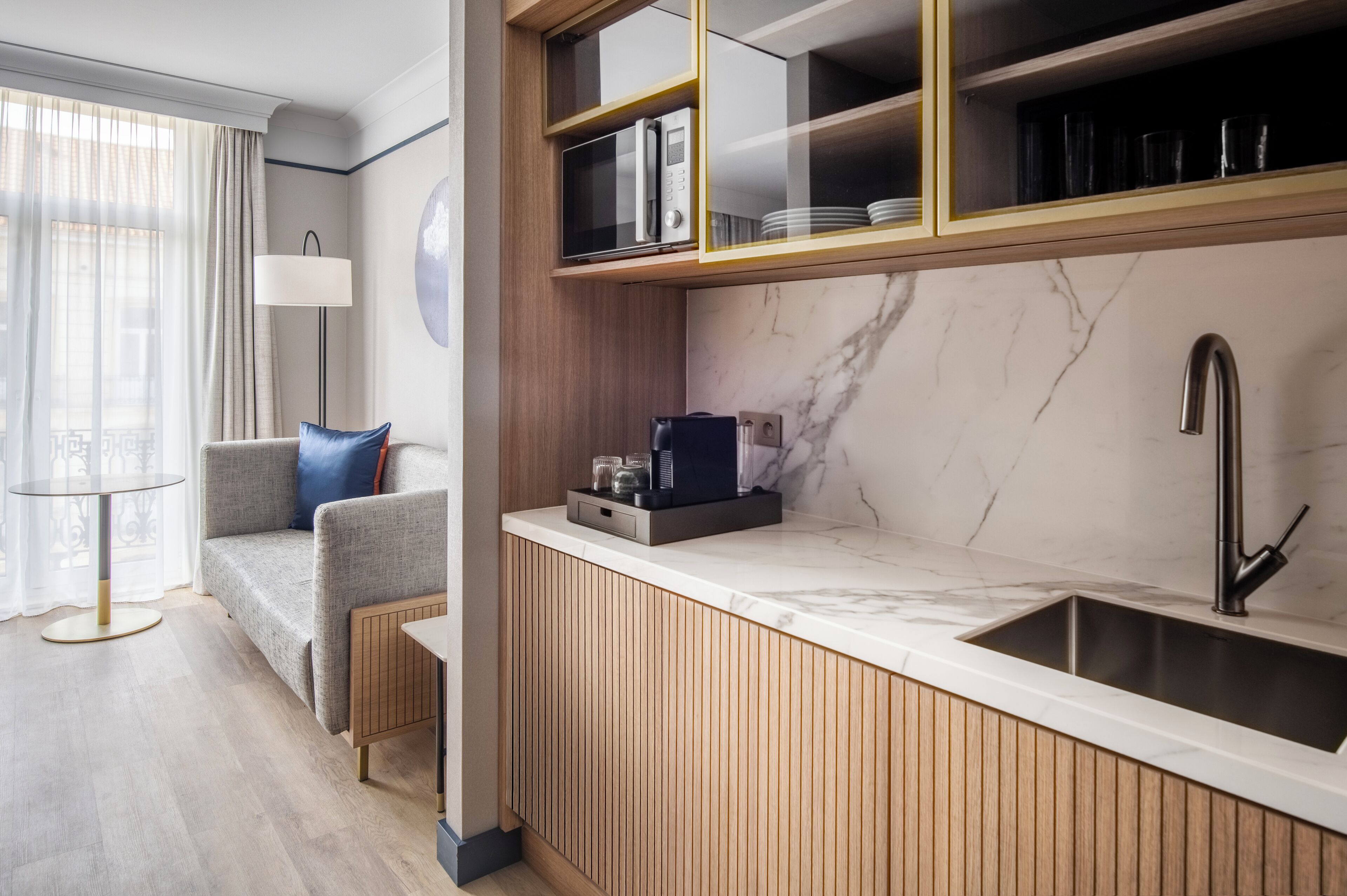 A modern kitchen with a built-in microwave, a sink, and a wooden cabinet.
