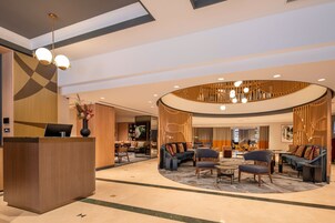 En moderne lobby med receptionsdisk, siddeområde og en buet træstruktur.