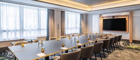 A conference room with a long table, chairs, and a projector screen.