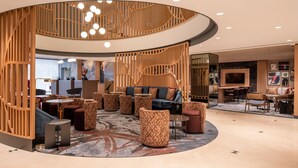 Un área de estar moderna con una disposición circular de asientos, una escalera central y una pantalla de televisión.
