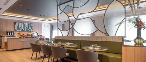 Un restaurant moderne doté d’un plancher en bois, d’un espace détente avec des sièges verts et d’un mur décoratif.