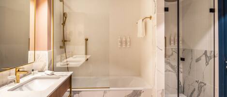 A modern bathroom with a large mirror, a bathtub, and a glass-enclosed shower area.