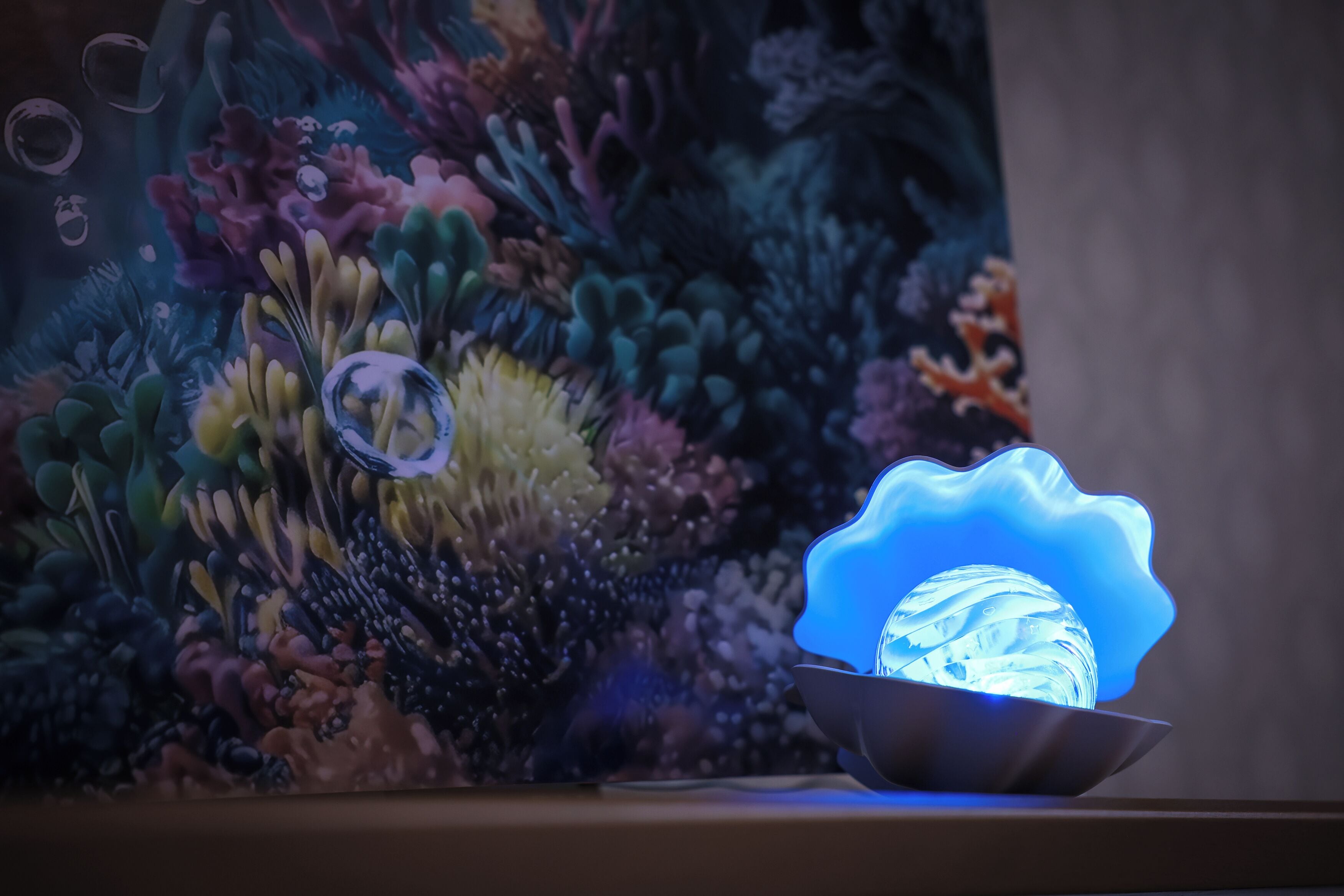 Un acquario decorativo con barriera corallina e una sfera di vetro illuminata di blu.