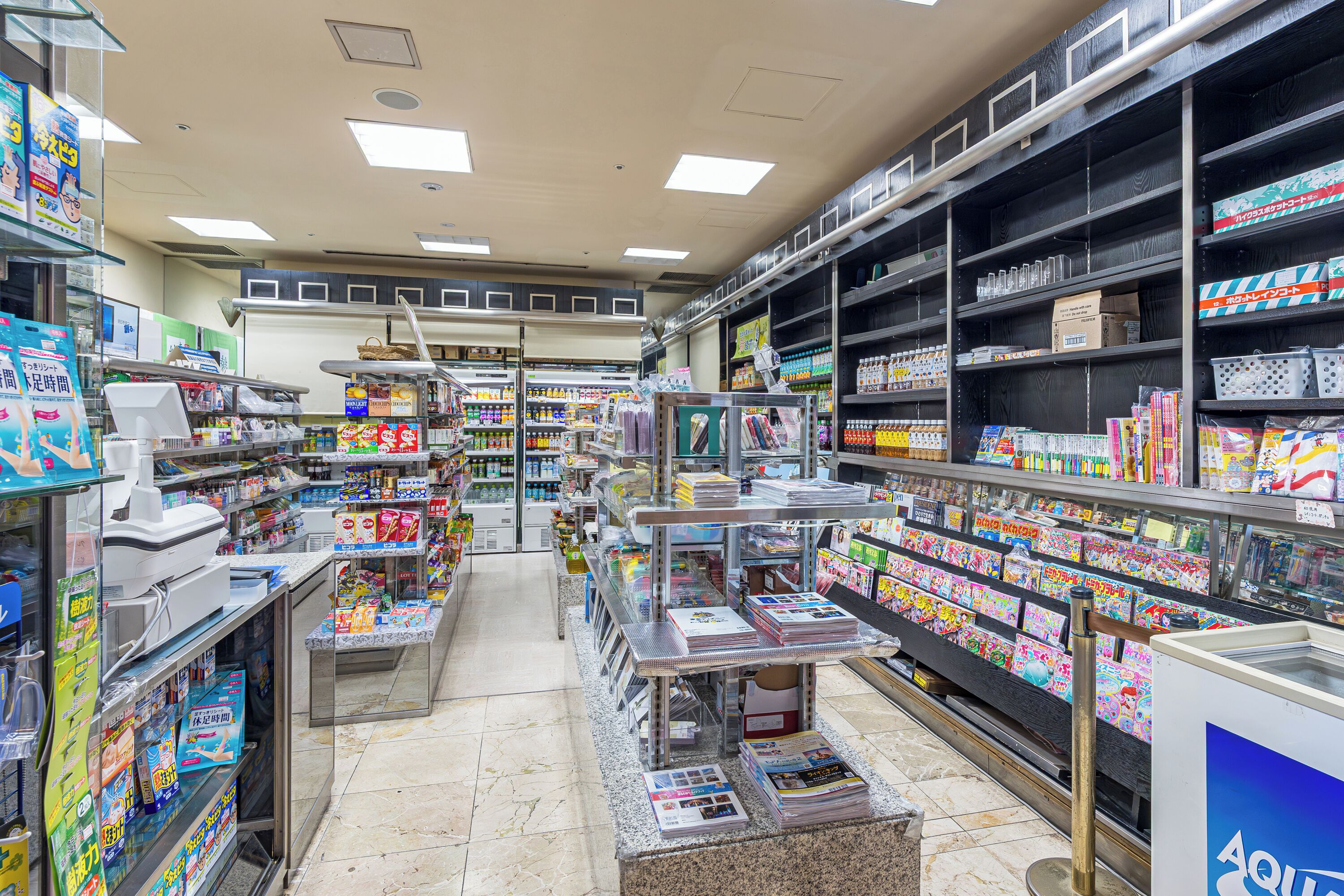 A well-organized bookstore with shelves stocked with various books and magazines, a checkout counter, and a clear path for customers.