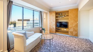 Una sala de estar moderna con un sofá, una mesa de centro de vidrio y un televisor sobre un mueble de pared de madera.