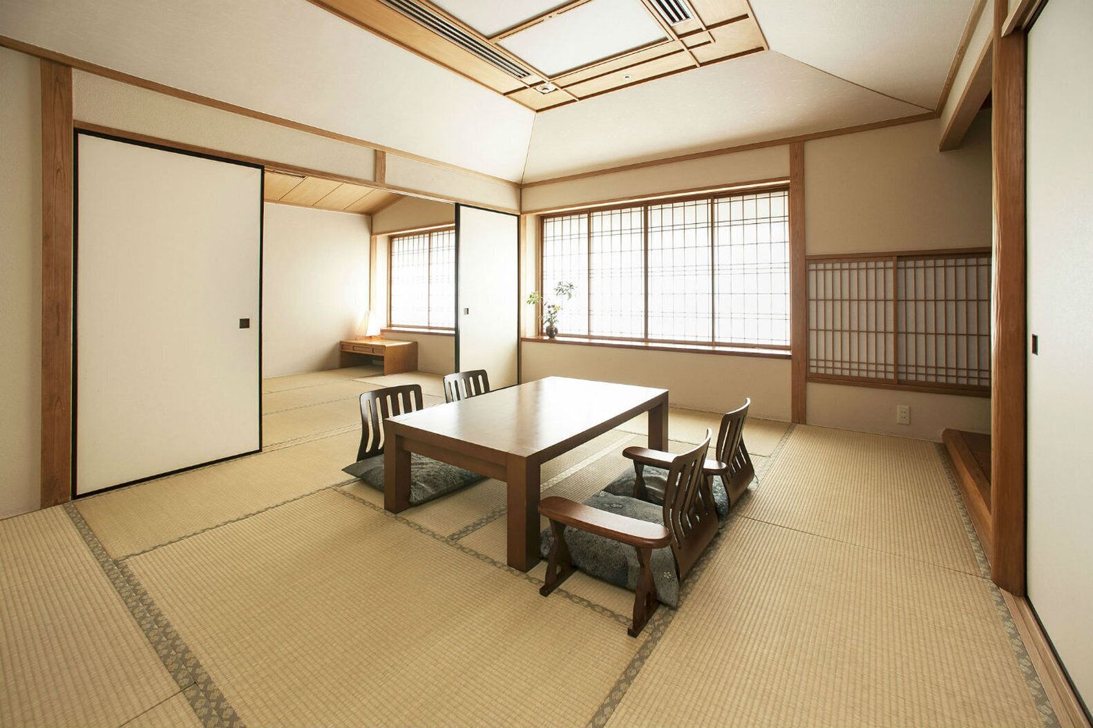 A traditional Japanese room with tatami flooring, a low table with chairs, and shoji screens.