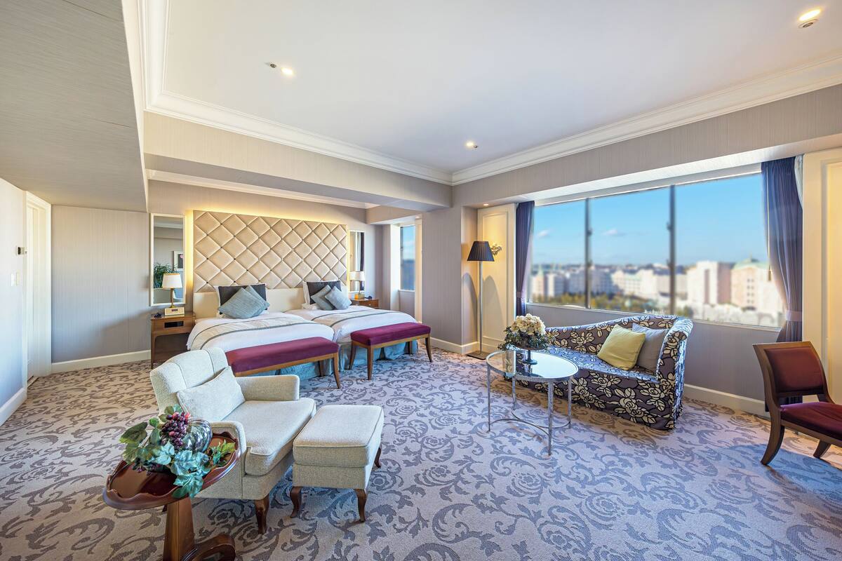 Une chambre d’hôtel avec un grand lit, deux tables de chevet, un canapé, une chaise et une petite table.