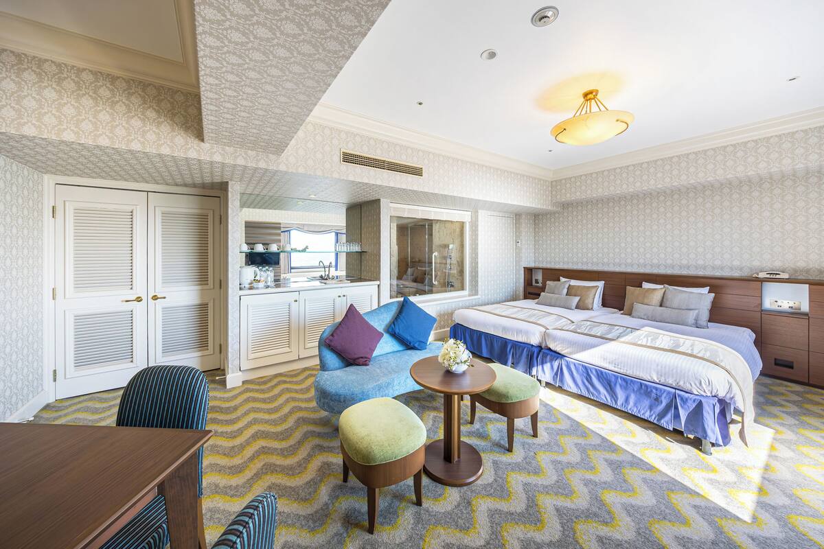 Une chambre d’hôtel comprenant un lit, un canapé, une table à manger et un petit coin cuisine.