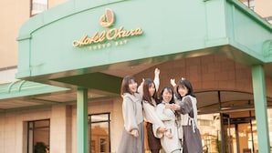 Entrada de un hotel con toldo verde y un letrero que dice 'Hotel Okura Tokyo Bay'.
