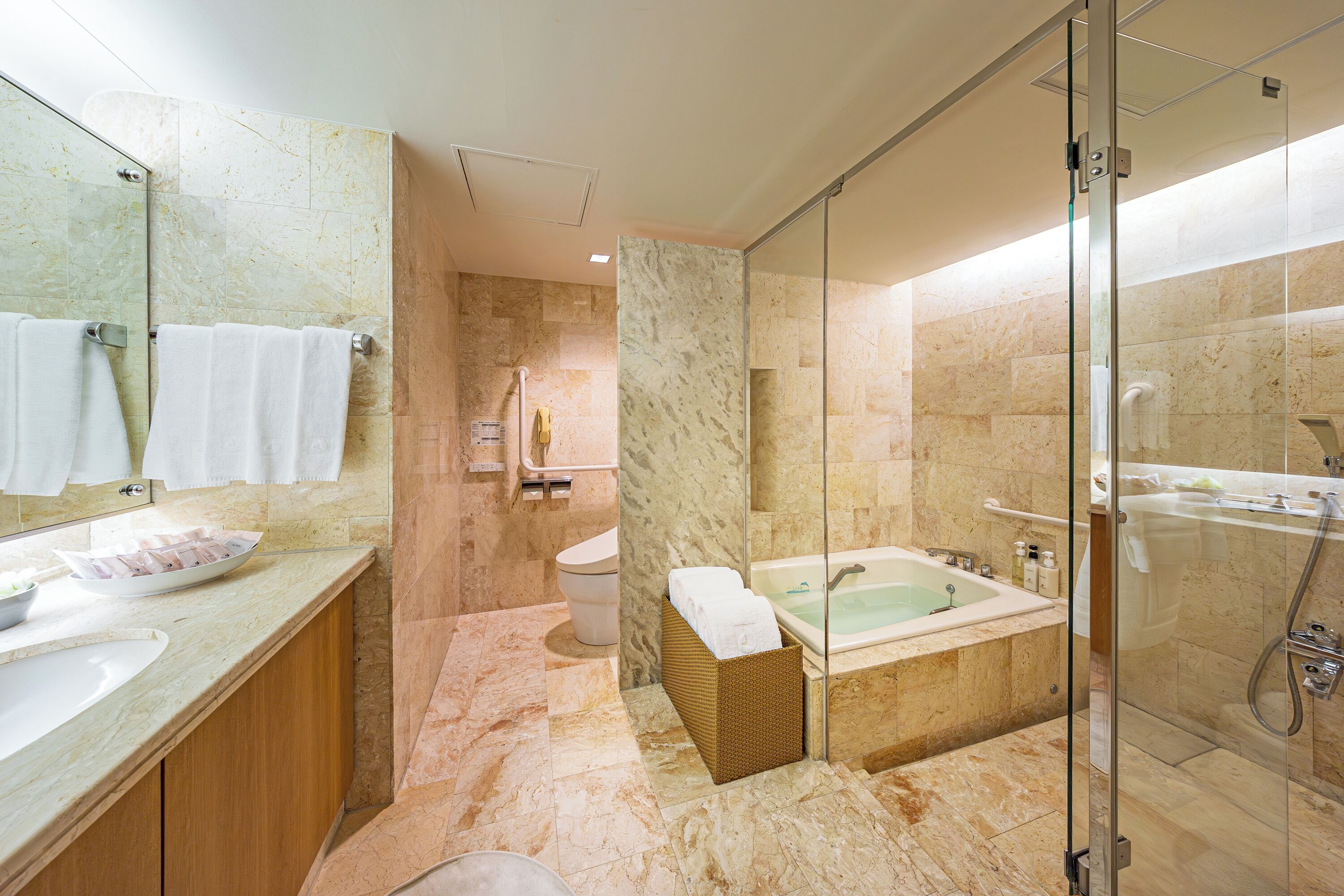 A modern bathroom with a marble floor, a glass-enclosed shower, a bathtub, and a large mirror.