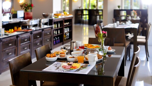 A dining area with a breakfast buffet, wooden furniture, and a view of the kitchen and dining room.