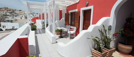 Un edificio rojo y blanco con un balcón blanco, una mesa y sillas.