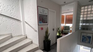Ein modernes Hotelinnere mit Treppe, einer gerahmten Karte an der Wand und Topfpflanzen.