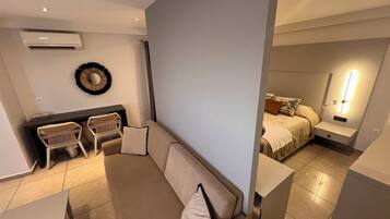A modern living room with a sofa, chairs, a small table, and a bed with a nightstand.