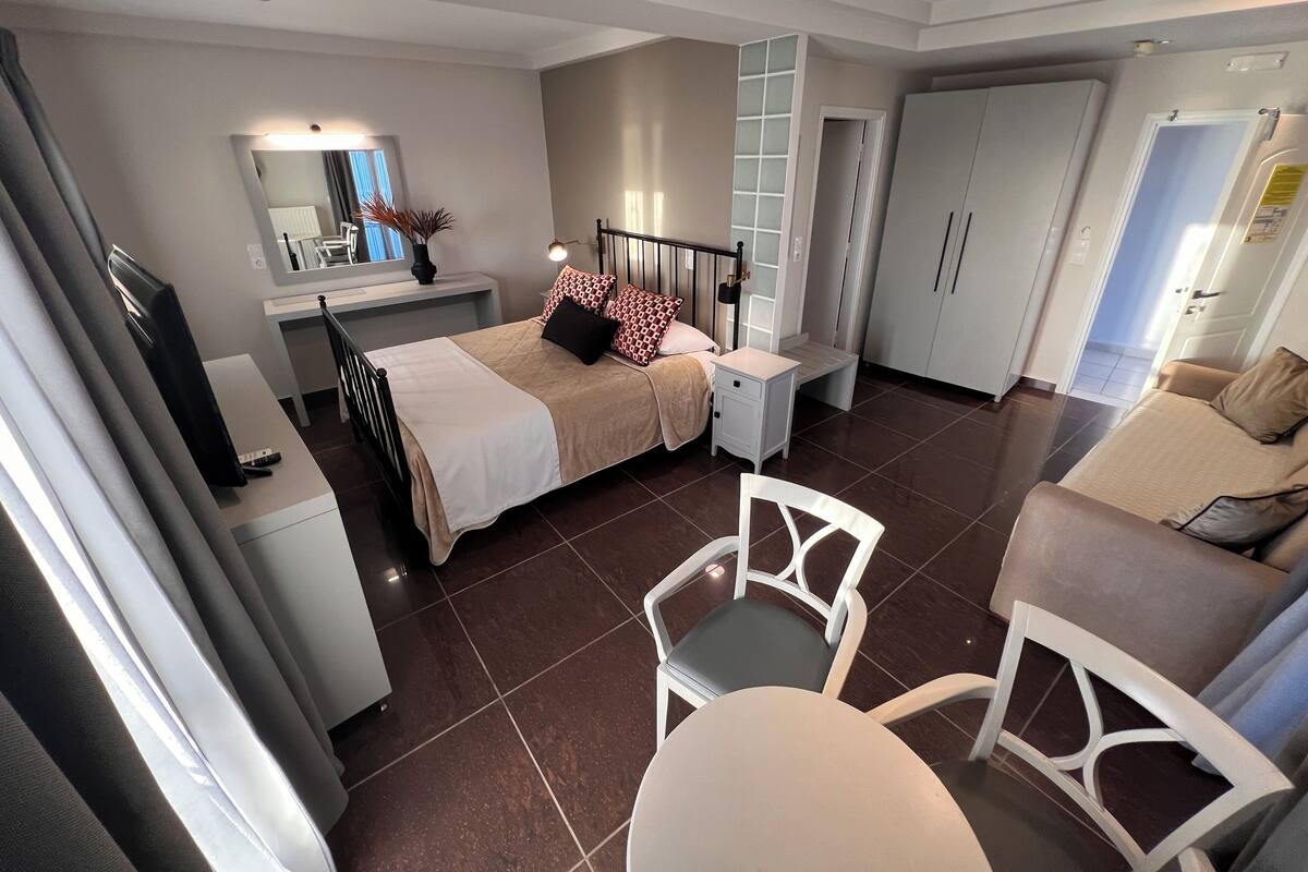 Een moderne slaapkamer met een bed, nachtkastjes, een televisie en een kledingkast.