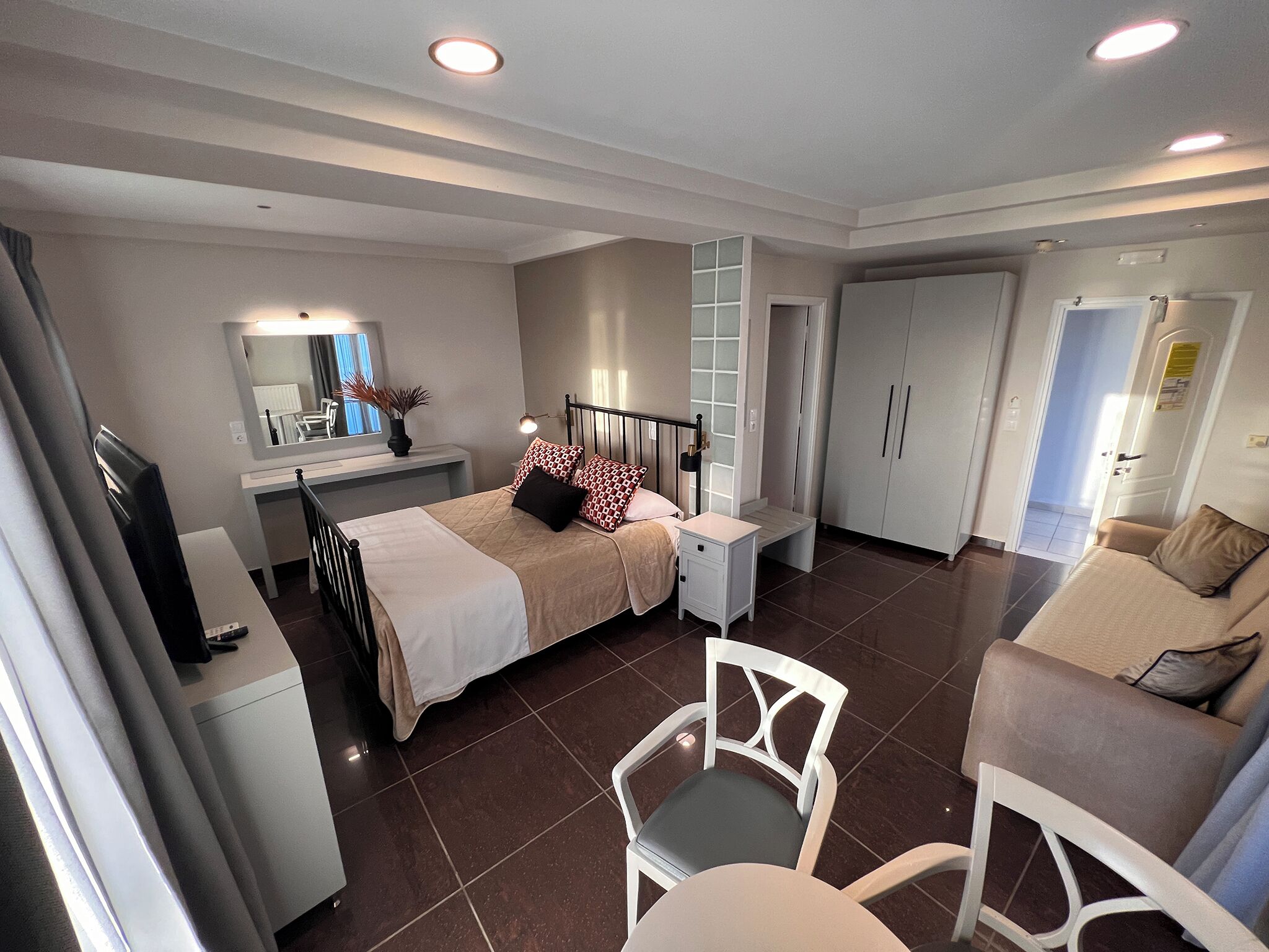 A bedroom with a bed, bedside table, lamp, wardrobe, and a chair.