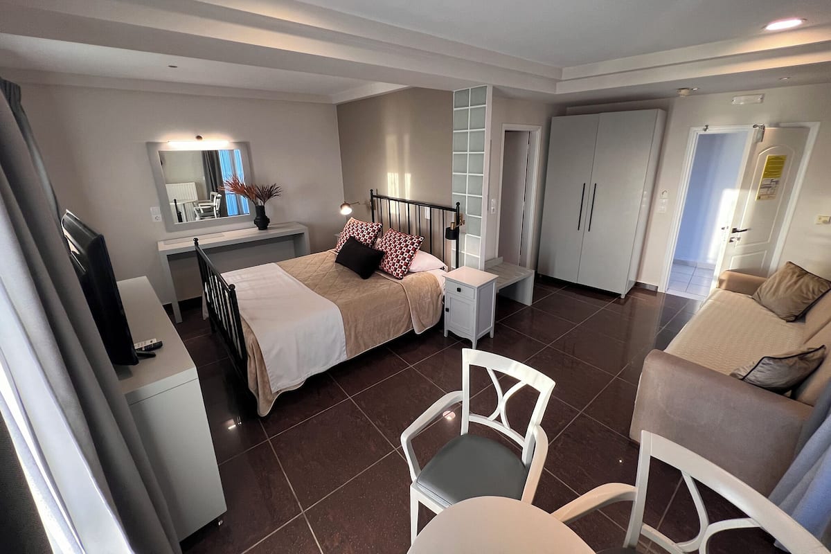 A bedroom with a bed, bedside table, lamp, wardrobe, and a chair.