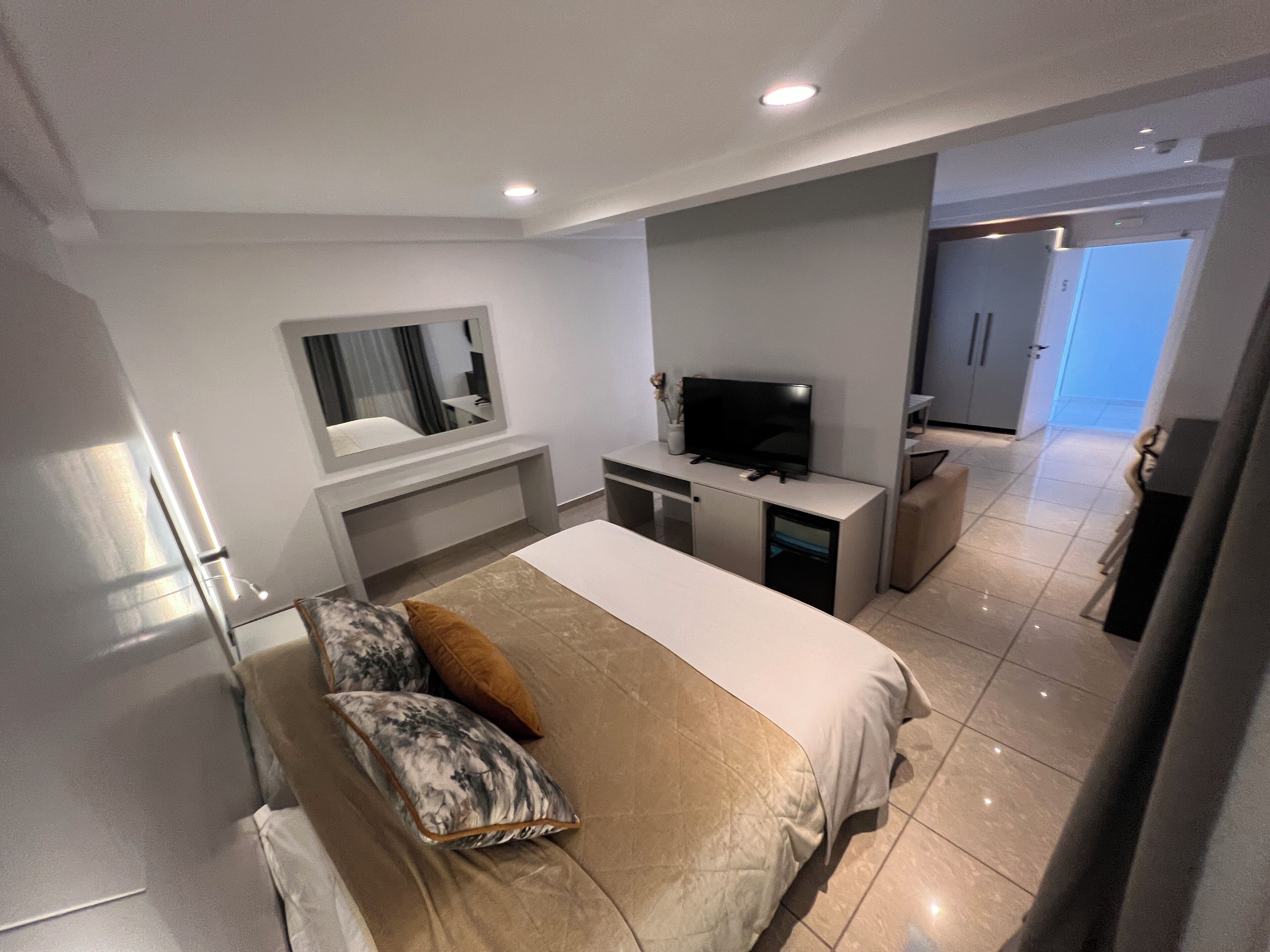 Une chambre d’hôtel moderne équipée d’un grand lit, d’un bureau, d’une télévision et d’un miroir.