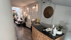 Ein moderner Empfangsbereich mit einem Holzbüro, einer Wanduhr und einem Blumentopf.