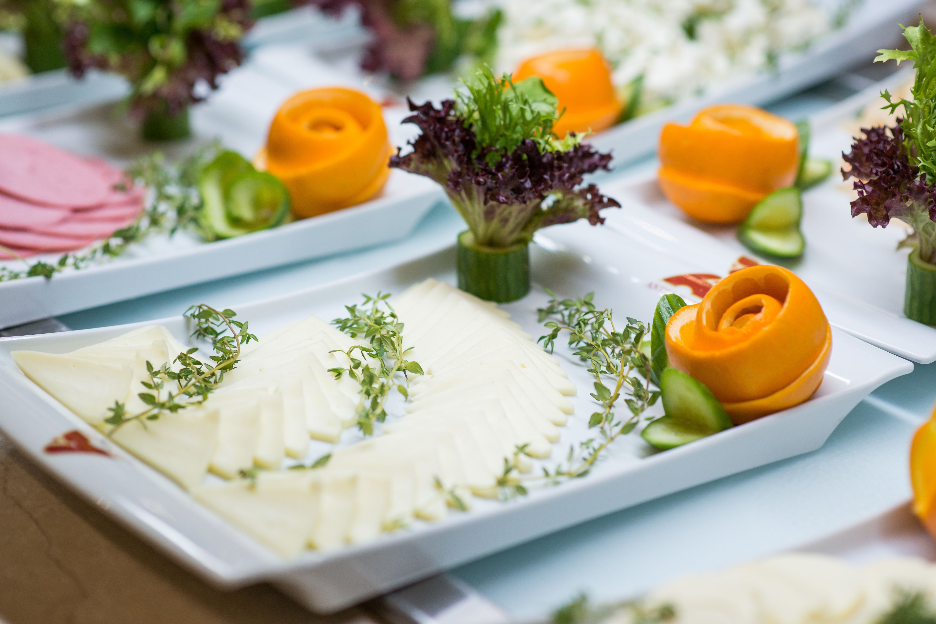 A buffet with various food items and garnishes on white rectangular plates.